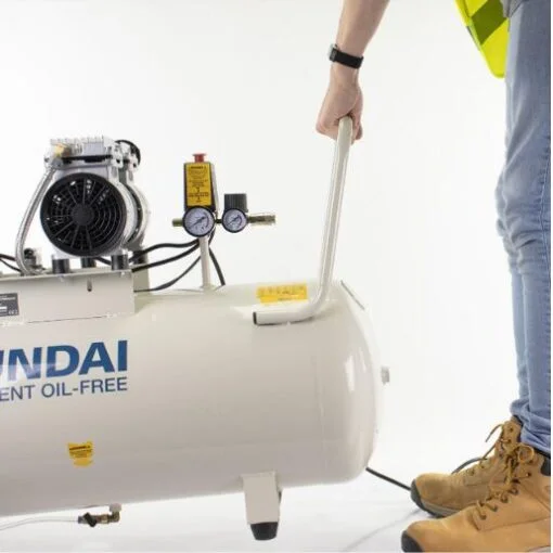 A man in a hi-viz top pulls the compressor by its handle